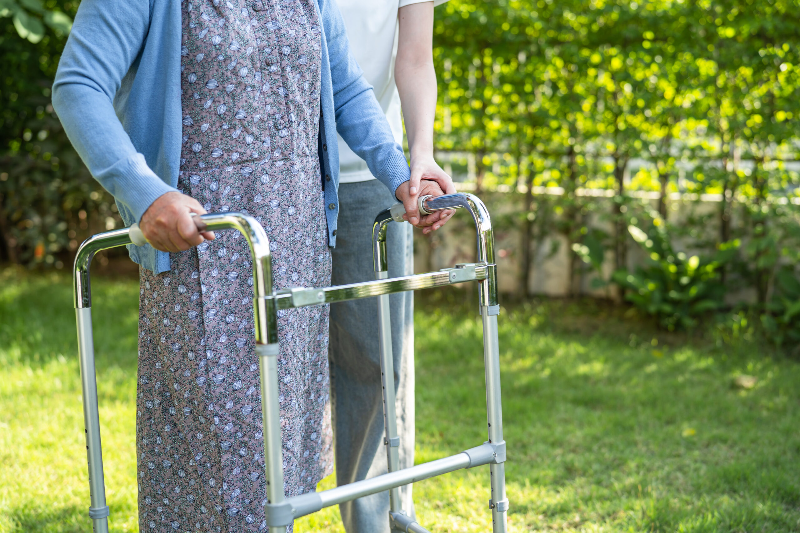 Caregiver help and care Asian senior or elderly old lady woman use walker with strong health while walking at park in happy fresh holiday.